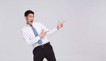 happy smiling young handsome Asian businessman pointing away and looking isolated on white studio background.