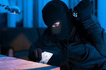 Burglar counting stolen money in dim light
