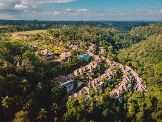 Drone view of luxury hotel with straw roof villas and pools in tropical jungle. Luxurious villa, pavilion in forest, Ubud, Bali. - 779953756