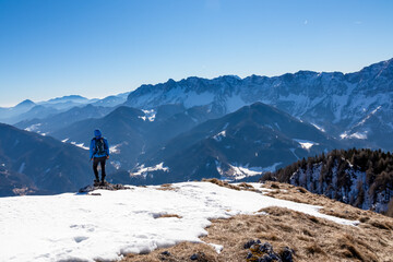 Man on panoramic hiking trail on way to snow covered mountain peak Ferlacher Horn in Carinthia,...