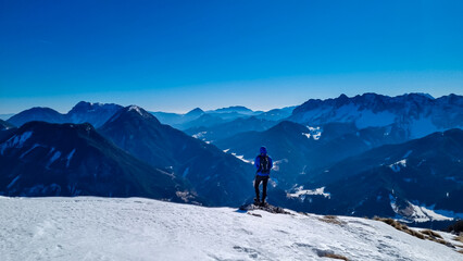 Man on panoramic hiking trail on way to snow covered mountain peak Ferlacher Horn in Carinthia,...
