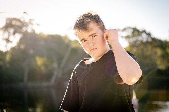 Teen boy standing in golden afternoon light with serious expression