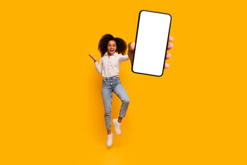 Energetic woman jump while holding smartphone with screen