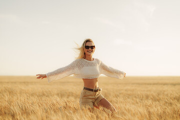 Relaxed young woman with open arms in a wheat field at sunset, feeling the essence of freedom and life.