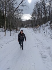 A woman hiking up a hill in the winter surrounded by a forest
