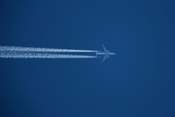 Airplane in the blue sky with contrails.
