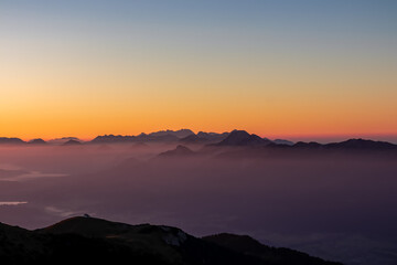 Panoramic sunrise view from Dobratsch on the Julian Alps and Karawanks in Austria, Europe. Silhouette of endless mountain ranges with orange and pink colors of sky. Jagged sharp peaks and valleys