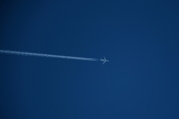 Airplane in the blue sky with contrails.