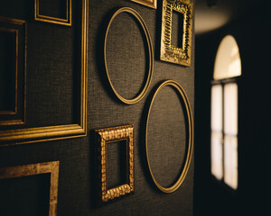 empty golden frames on dark wall in a corridor with natural light