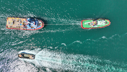 Aerial drone top down photo of industrial tug assisting boat cruising in deep blue Mediterranean sea