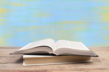 Composition with hardback books, fanned pages on wooden deck table and blue background. Books stacking. Back to school. Copy Space. Education background.
