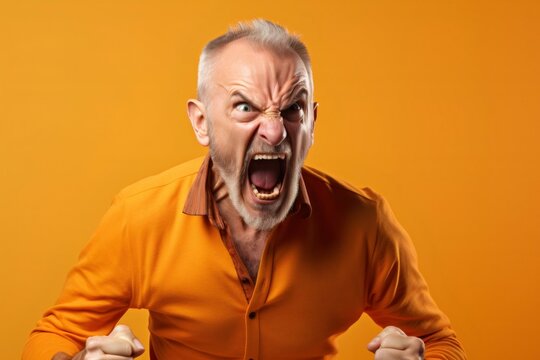 Screaming, hate, rage. Crying emotional angry senior man with open mouth screaming in colorful bright yellow studio background. Emotional, mature face. Human emotions, facial expression concept