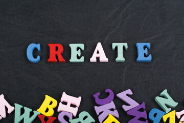 CREATE word on black board background composed from colorful abc alphabet block wooden letters, copy space for ad text. Learning english concept.