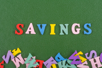 SAVINGS word on green background composed from colorful abc alphabet block wooden letters, copy space for ad text. Learning english concept.