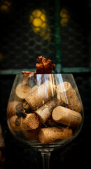 The clear glass wine glass is elegantly filled with a colorful array of used wine corks, each one a testament to memorable evenings and cherished moments shared over a glass of wine.