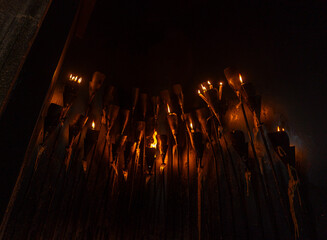 Torches with lit wax candles forming a gathering of people to pray and hold vigil for hope and divine forgiveness. - obrazy, fototapety, plakaty