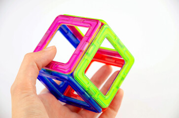 A cube made of colorful transparent magnet squares (puzzle builder for kids), closeup in a hand...
