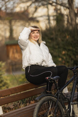 Woman Enjoying Sunny Day on Park Bench Next to Bicycle