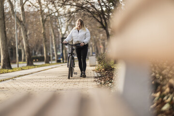 Woman Walking Bicycle Down Sidewalk