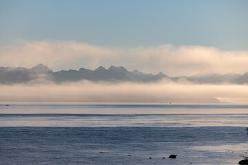 Misty lake framed by mountains, creating a serene natural landscape - 779988136