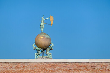 Scenic view of Dogana del Mar statue in Venice, Veneto, Northern Italy, Europe. Two atlases carry the globe on which a statue of Fortuna stands. Golden landmark. Clear blue sky in background - obrazy, fototapety, plakaty