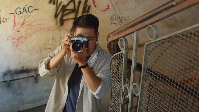 High angle view of Asian man taking photos inside abandoned house with shabby graffitied walls