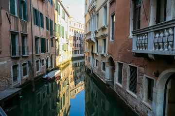 Fototapeta na wymiar Floating boats with panoramic view of a water channel in city of Venice, Veneto, Italy, Europe. Venetian architectural landmarks and old houses facades along water canal. Urban tourism in summer