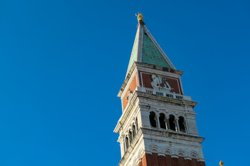 Fototapeta na wymiar Scenic view of the bell tower St Mark's Campanile on San Marco town square in Venice, Veneto, Northern Italy, Europe. Venetian architectural landmarks with blue background. Urban summer tourism