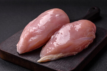 Fresh chicken fillet on a dark concrete table with spices and herbs