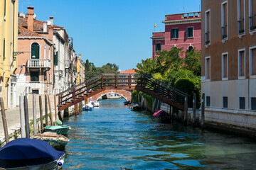 Floating boats with panoramic view of a water channel in city of Venice, Veneto, Italy, Europe. Venetian architectural landmarks and old houses facades along water canal. Urban tourism in summer