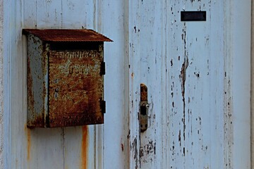 Old rusty mailbox on a wooden white door
