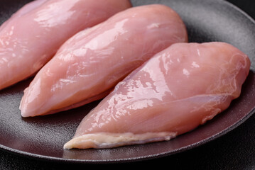 Fresh chicken fillet on a dark concrete table with spices and herbs