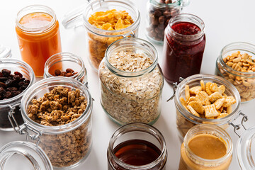 food storage and eating concept - close up of jars with oat, corn flakes, granola, cookies and...