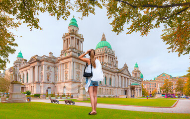 A beautiful blonde woman in mini shorts is standing and watching the surroundings - City Hall of Belfast - Northern Ireland, United Kingdom