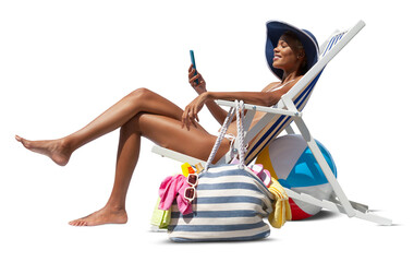 Happy woman at the beach on deck chair, sunbathing, uses the mobile phone, isolated in the white background, concept a summer beach holiday, online shopping, booking travel, and resorts accommodations