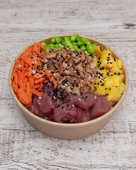 Takeaway poke bowl with fresh tuna,mango, edamame,carrot, and crispy onion in recycled kraft paper...