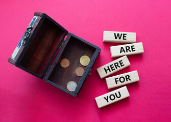 Help symbol. Wooden blocks with words We are here for you. Beautiful red background with money box. Business and We are here for you concept. Copy space.