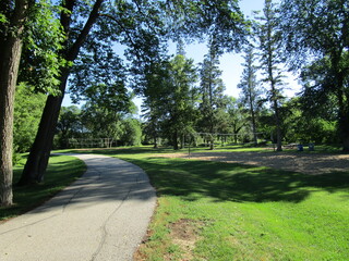 paved walking path through a park with sand volleyball courts