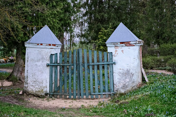 old crooked cemetery gate with white columns. Jačūnu kapi, Latvia, Zemgale