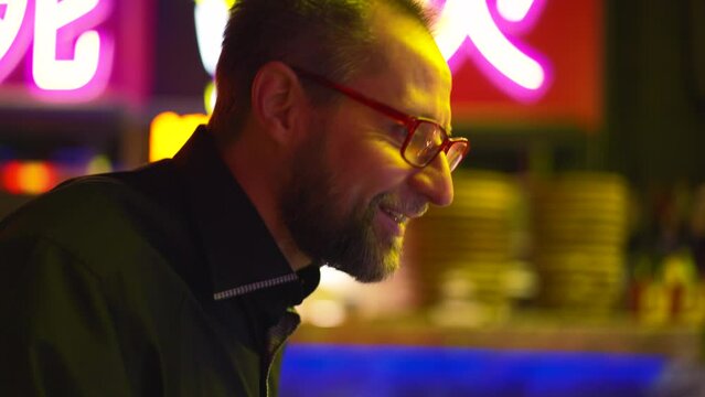 Hands deftly navigate pinball levers, transition to man's face, alight with leisurely joy in Asia cafe. Closeup captures switch from play to player, embodying carefree pastime. Concept; entertainment