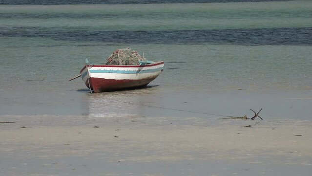 Tunisia fishing industry and natural landscapes, small wooden fishing boat stranded on an idyllic beach at Djerba island, a popular holiday destination
