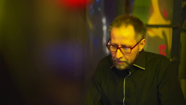 Amidst the neon glow, man's game is interrupted by a phone alert. Camera movements reflect player's nervousness. This clip exemplifies the sudden pull from addiction's grip to life's realities