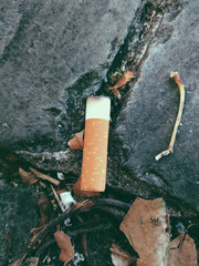 Cigarette butt thrown out on the street. There are ash left on the cigarette butt