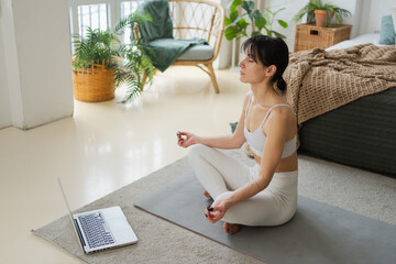 Yoga mindfulness meditation online. Woman practicing yoga with online lessons in laptop at home....