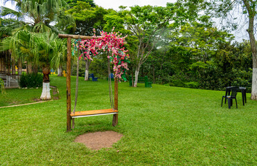 Garden bench decorated with flowers. Surrounded by beautiful trees. Beautiful lawn.
