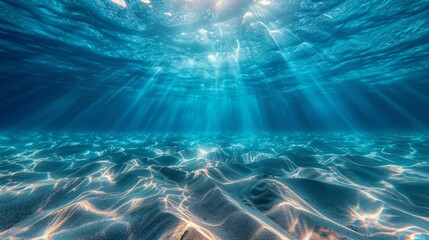 Underwater view with sunrays shining over sandy seabed