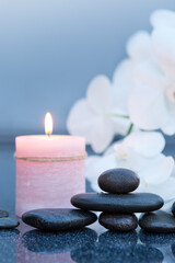 Fototapeta na wymiar Spa background with white orchid , candle and zen black stones on gray.