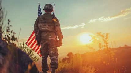Tuinposter Young soldier holding gun and american flag © Kateryna