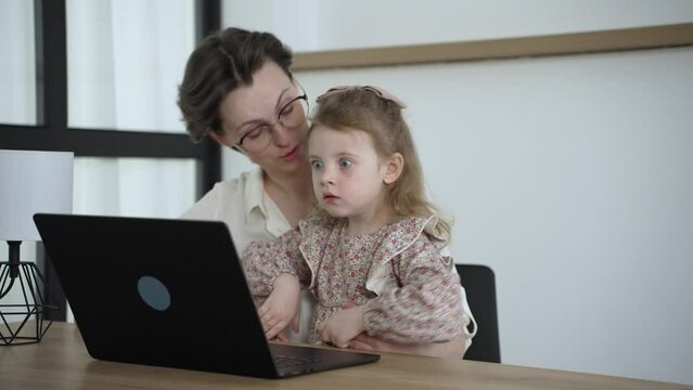 Cheerful woman her little daughter spend free time together at home relaxing on couch with laptop device