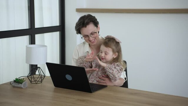 Cheerful woman her little daughter spend free time together at home relaxing on couch with laptop device